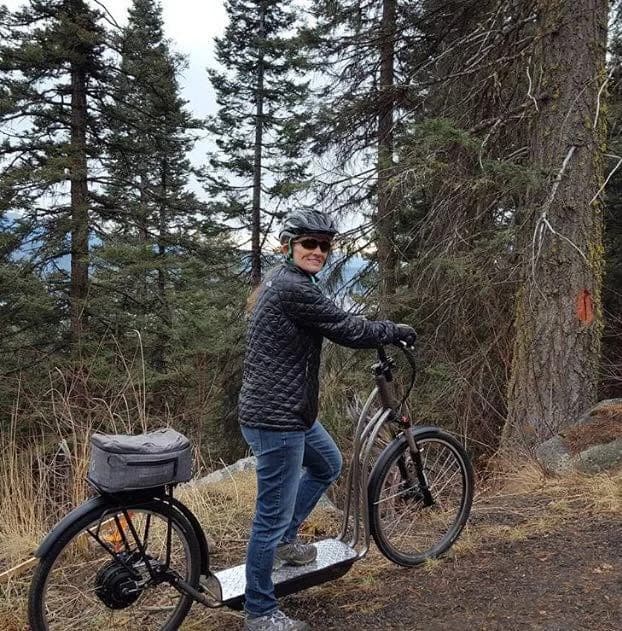 Rider standing on an early NF scooter on a forested mountain road
